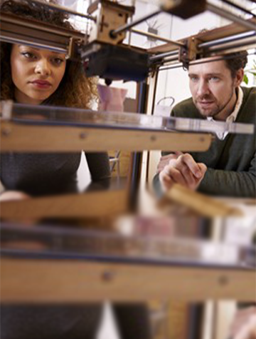 A Man and a Woman Looking at the Inside of a 3D Printer